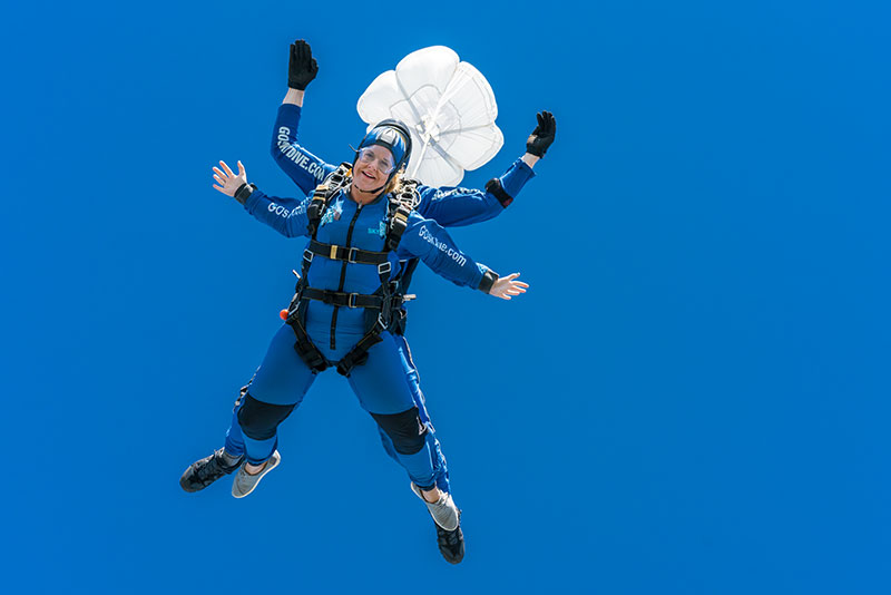Skydiver facing cameraman in freefall with blue sky
