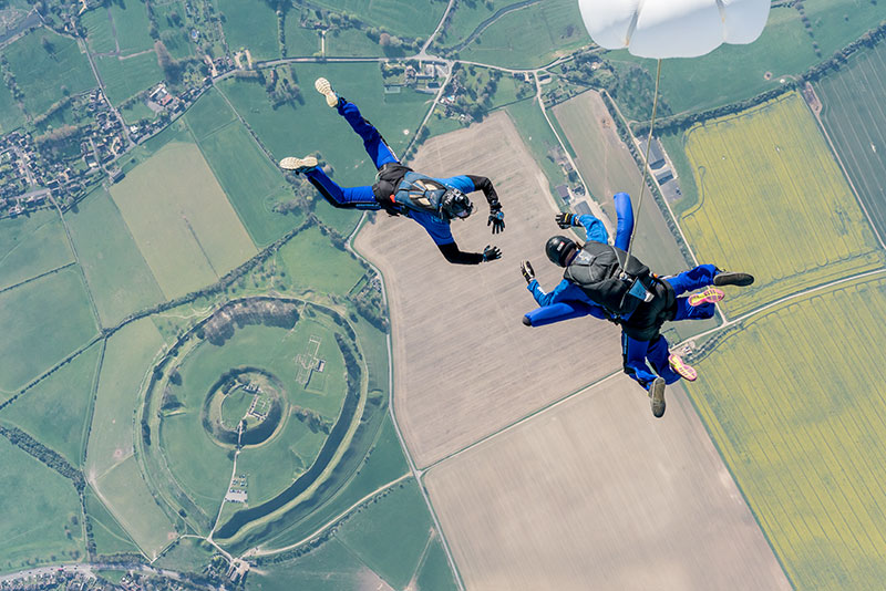 Tandem Skydivers with cameraman in freefall. Shot is taken form above.