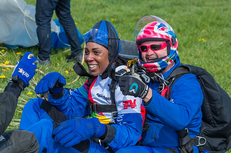 Skydiver smiling with instructor after landing
